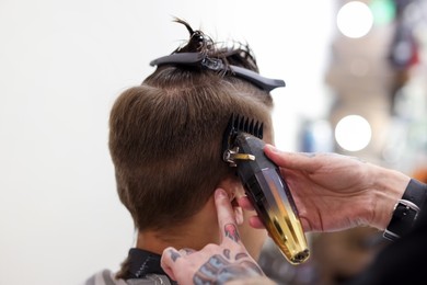 Photo of Professional barber making stylish haircut in barbershop, closeup