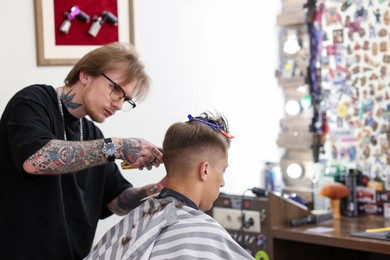 Photo of Professional barber making stylish haircut in barbershop