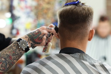 Photo of Professional barber making stylish haircut in barbershop, closeup