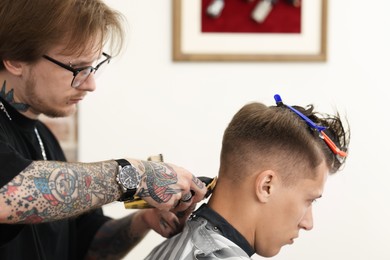 Photo of Professional barber making stylish haircut in barbershop