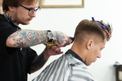 Photo of Professional barber making stylish haircut in barbershop