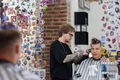 Photo of Professional barber making stylish haircut in barbershop