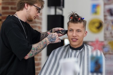Photo of Professional barber making stylish haircut in barbershop