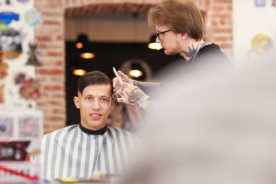 Photo of Professional barber making stylish haircut in barbershop