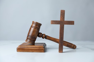 Photo of Judge's gavel and wooden cross on white marble table