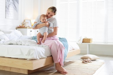 Photo of Mother and her cute baby on bed at home. Space for text