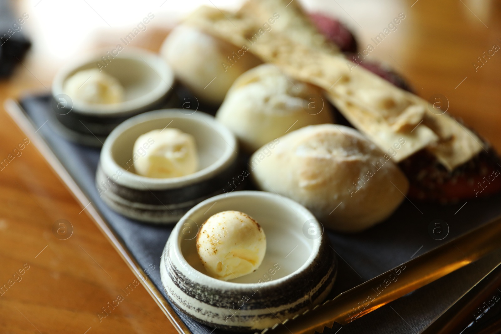 Tasty buns, crackers and butter served on wooden table, closeup Photo of Tasty buns, crackers and butter served on wooden table, closeup