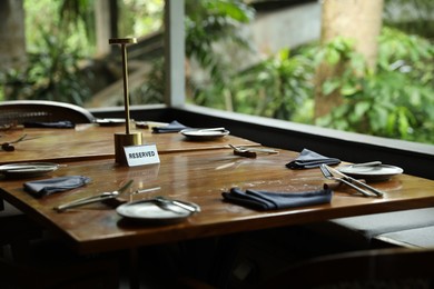 Photo of Sign with word Reserved on wooden table in restaurant