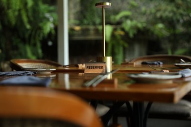 Photo of Sign with word Reserved on wooden table in restaurant