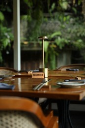 Photo of Sign with word Reserved on wooden table in restaurant