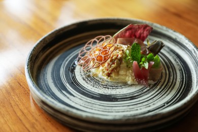 Photo of Tasty burrata ham salad served on wooden table, closeup