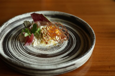 Photo of Tasty burrata ham salad served on wooden table, closeup