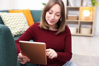 Photo of Woman with modern tablet on floor at home