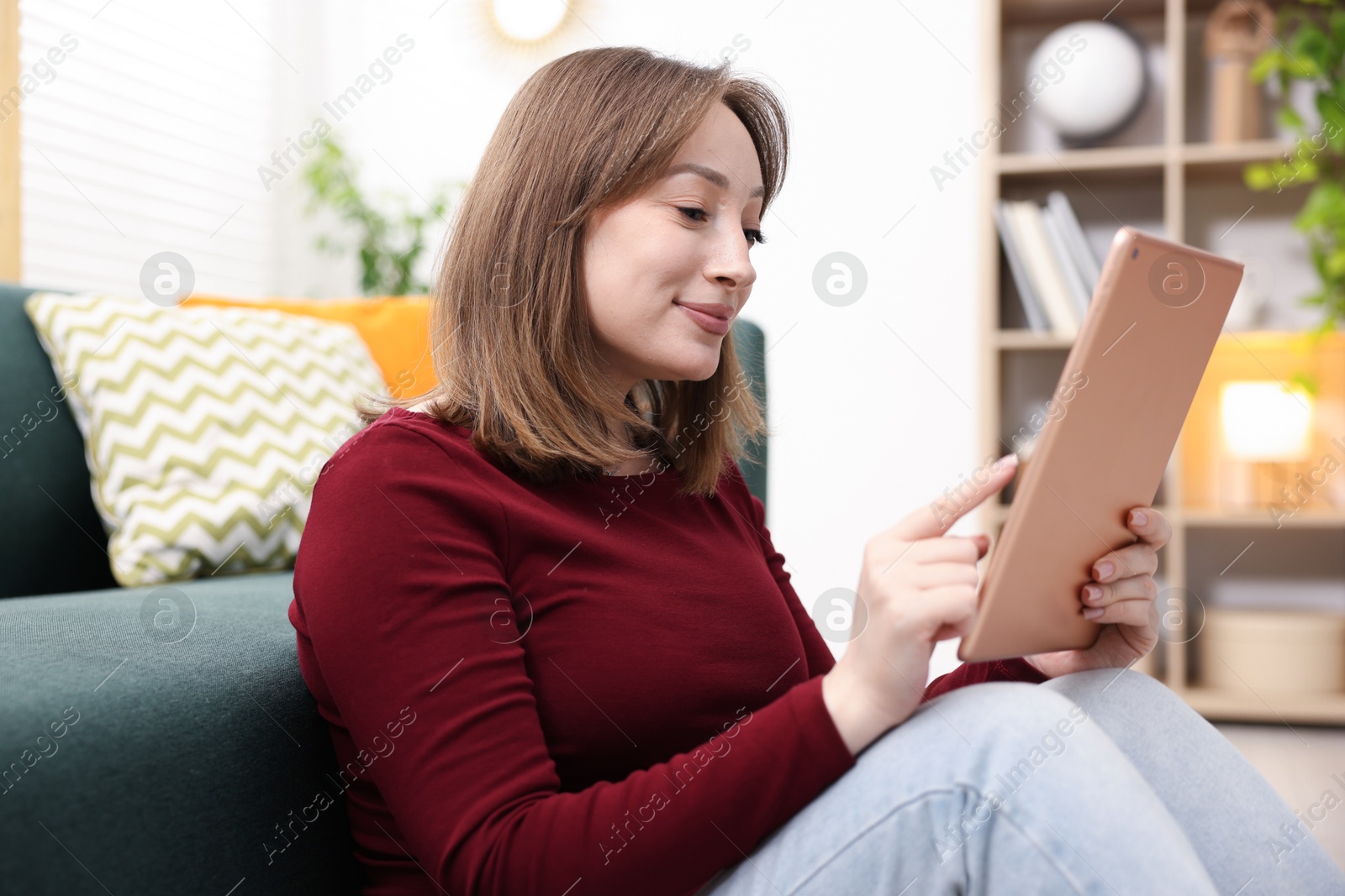 Woman with modern tablet on floor at home Photo of Woman with modern tablet on floor at home