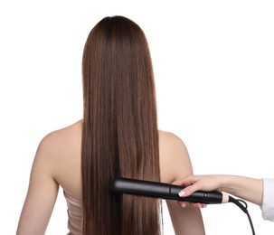Photo of Hairdresser straightening woman's hair on white background, back view