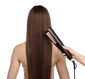 Photo of Hairdresser straightening woman's hair on white background, back view