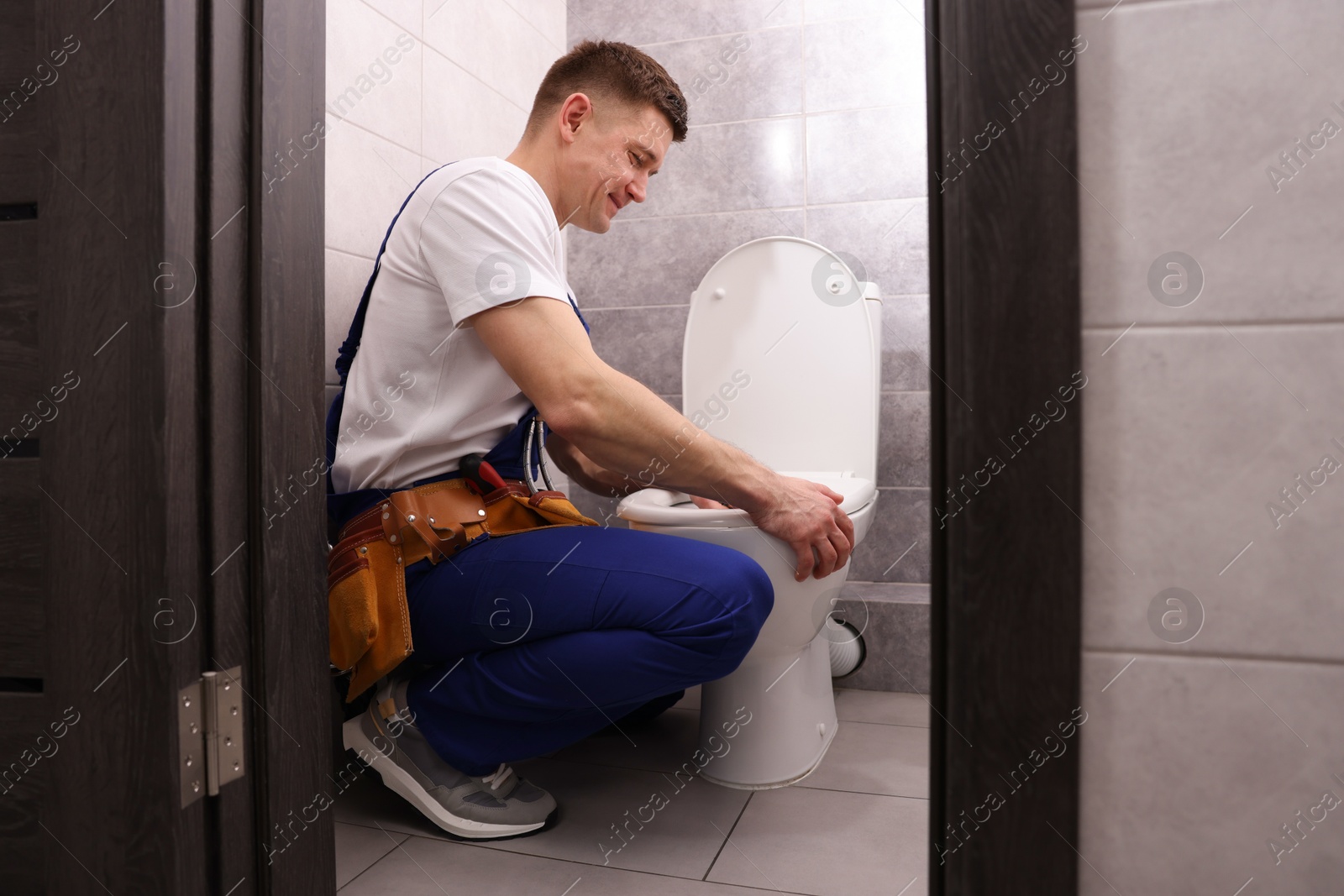 Plumber unclogging toilet with hand plunger indoors Photo of Plumber unclogging toilet with hand plunger indoors