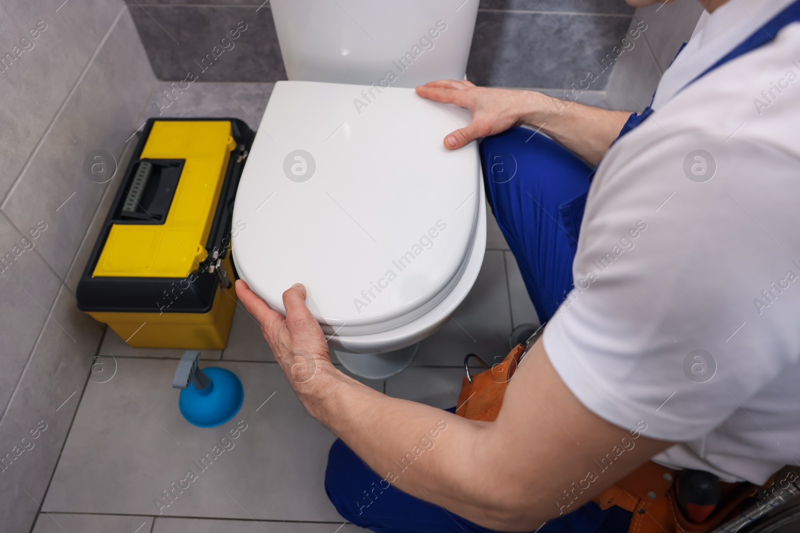 Professional plumber repairing toilet bowl in restroom, closeup Photo of Professional plumber repairing toilet bowl in restroom, closeup