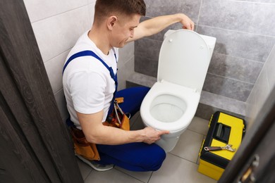 Photo of Plumber flushing toilet after repairing it indoors