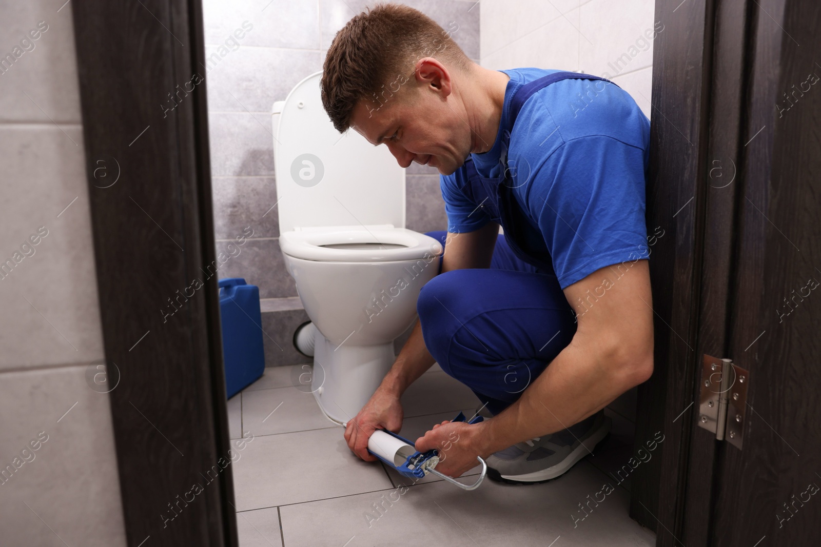 Professional plumber sealing toilet bowl in restroom Photo of Professional plumber sealing toilet bowl in restroom