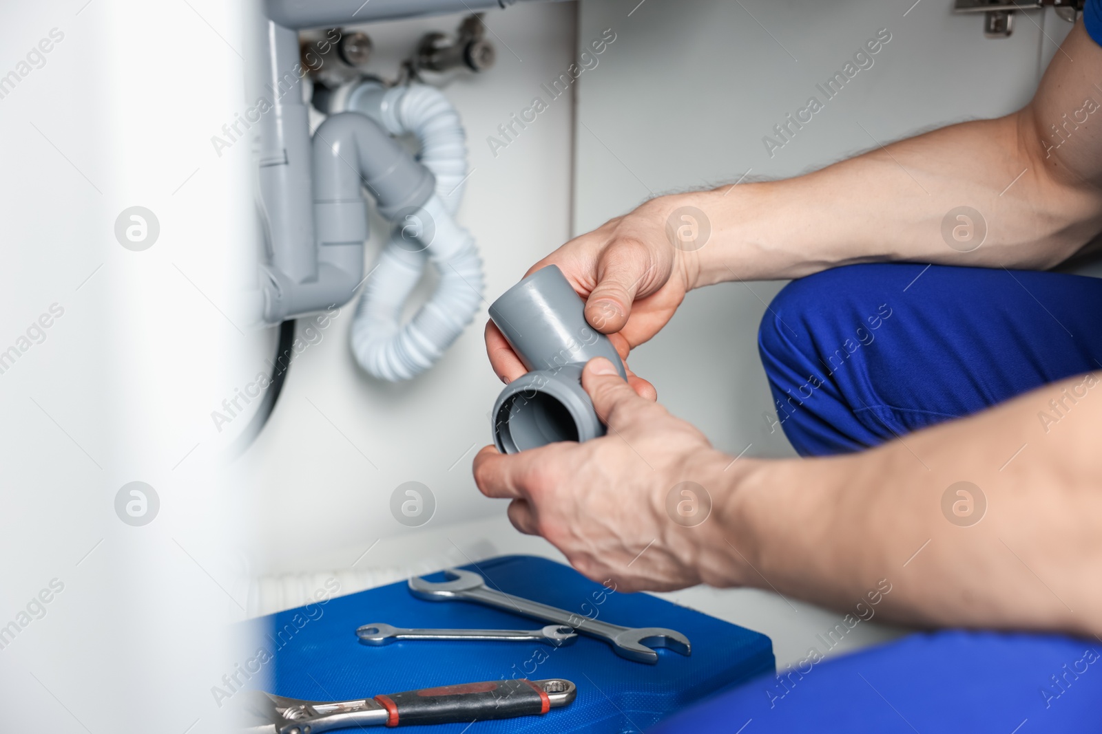 Plumber fixing pipes under sink indoors, closeup Photo of Plumber fixing pipes under sink indoors, closeup