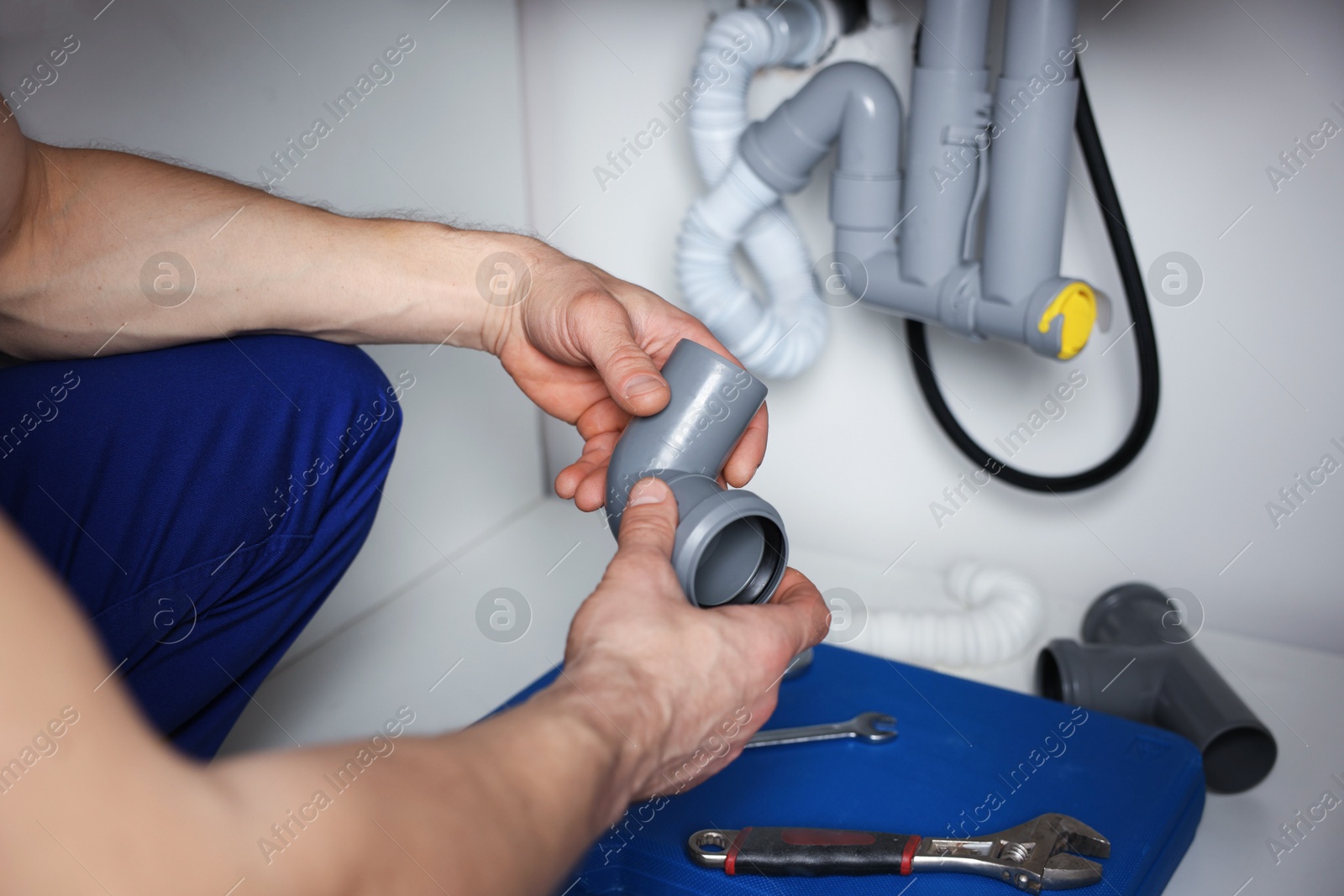 Plumber fixing pipes under sink indoors, closeup Photo of Plumber fixing pipes under sink indoors, closeup