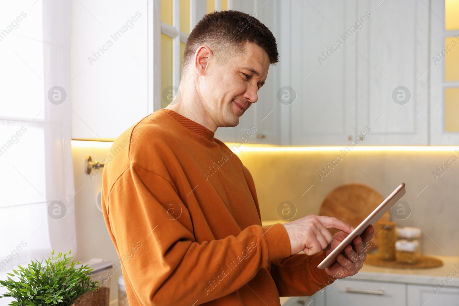 Man using modern tablet in kitchen at home Photo of Man using modern tablet in kitchen at home