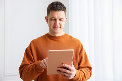 Photo of Man using modern tablet at white wall