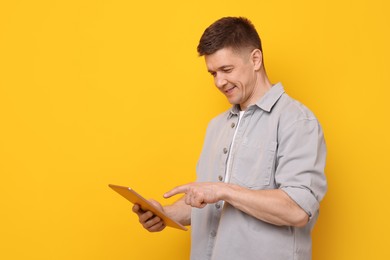 Photo of Man using modern tablet on yellow background. Space for text