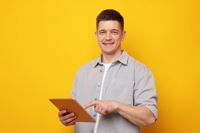 Photo of Man using modern tablet on yellow background. Space for text