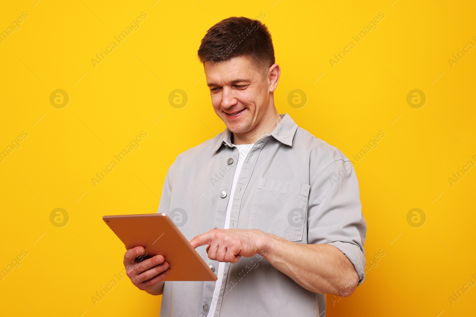 Man using modern tablet on yellow background Photo of Man using modern tablet on yellow background