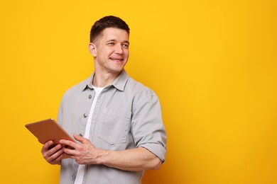 Photo of Man using modern tablet on yellow background. Space for text