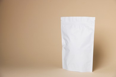 Photo of One zipper stand-up pouch on beige background. Mockup for design