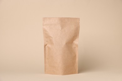 Photo of One zipper stand-up pouch on beige background. Mockup for design
