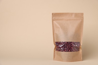 Photo of One zipper stand-up pouch with kidney beans on beige background. Mockup for design