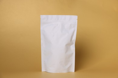 Photo of One zipper stand-up pouch on light orange background. Mockup for design