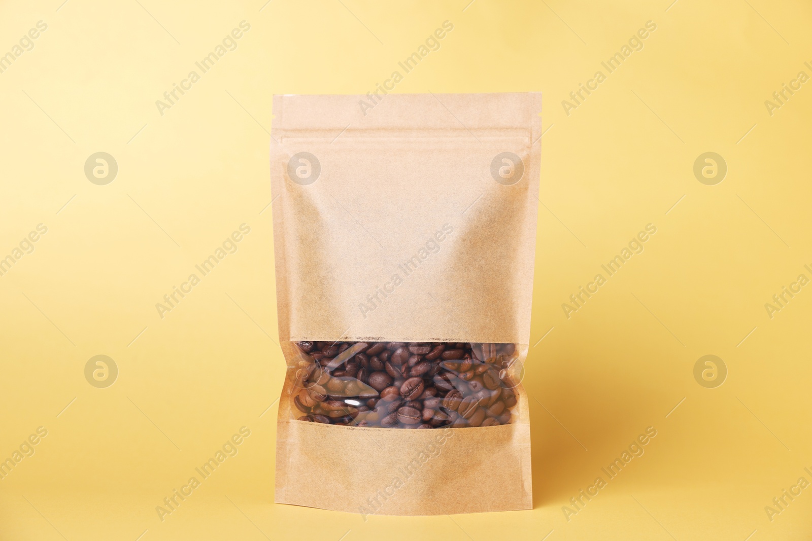 One zipper stand-up pouch with coffee beans on light orange background. Mockup for design Photo of One zipper stand-up pouch with coffee beans on light orange background. Mockup for design