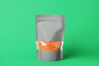 Photo of One zipper stand-up pouch with lentils on green background. Mockup for design