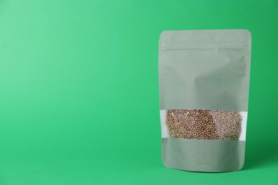 Photo of One zipper stand-up pouch with seeds on green background. Mockup for design