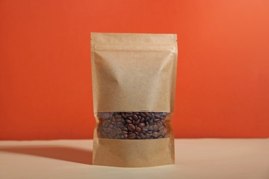 Photo of One zipper stand-up pouch with coffee beans on white table against red background. Mockup for design