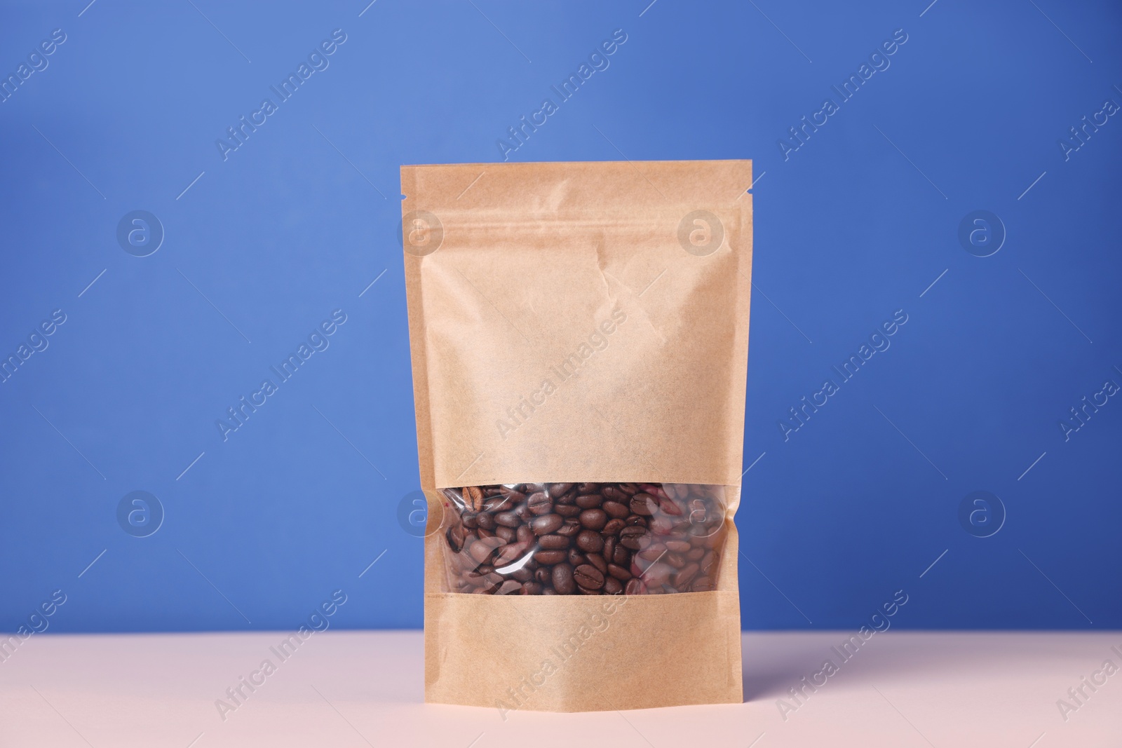 One zipper stand-up pouch with coffee beans on white table against blue background. Mockup for design Photo of One zipper stand-up pouch with coffee beans on white table against blue background. Mockup for design
