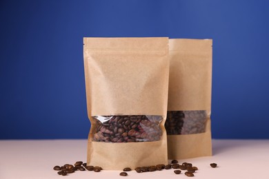 Photo of Zipper stand-up pouches with coffee beans on pink table against blue background. Mockup for design