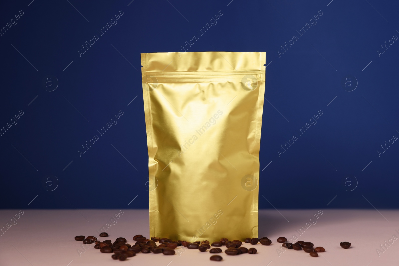 One zipper stand-up pouch with coffee beans on pink table against blue background. Mockup for design Photo of One zipper stand-up pouch with coffee beans on pink table against blue background. Mockup for design