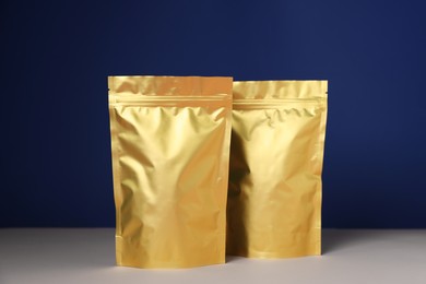 Photo of Zipper stand-up pouches on white table against blue background. Mockup for design