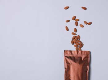 Photo of One zipper stand-up pouch with almonds on light grey background, flat lay. Mockup for design