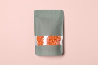 Photo of One zipper stand-up pouch with lentils on pink background, top view. Mockup for design
