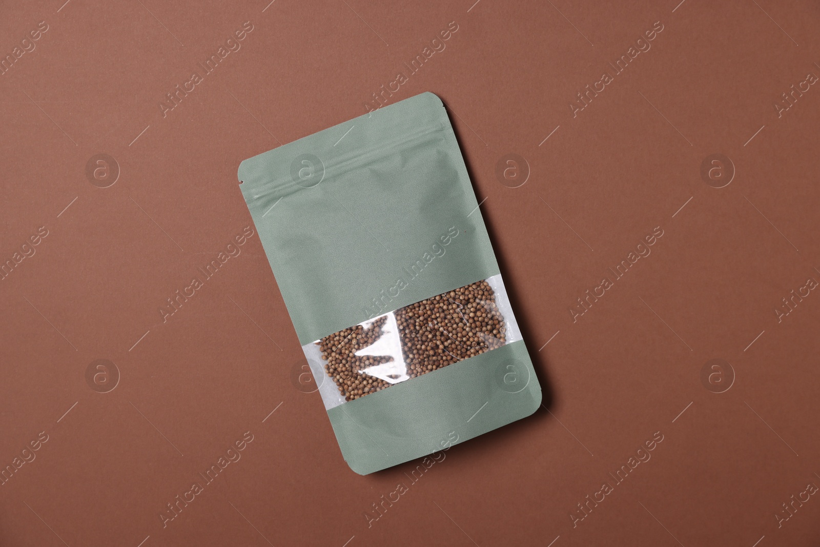 Photo of One zipper stand-up pouch with seeds on brown background, top view. Mockup for design