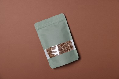 Photo of One zipper stand-up pouch with seeds on brown background, top view. Mockup for design