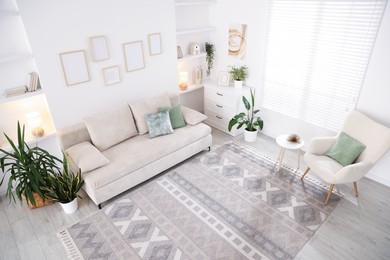 Photo of Comfortable sofa and stylish rug in room, above view. Interior design
