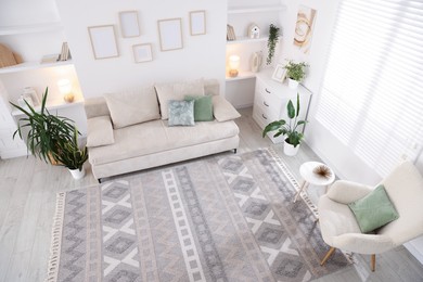 Photo of Comfortable sofa and stylish rug in room, above view. Interior design
